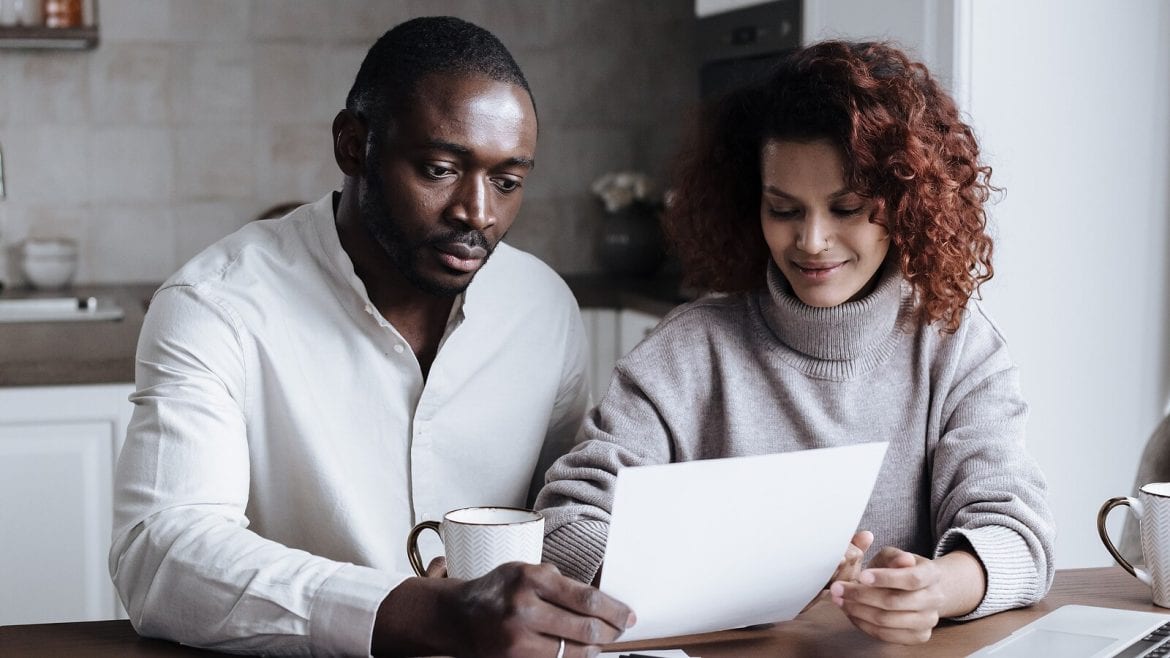 A couple at a kitchen table looking at documents, appearing calm and focused